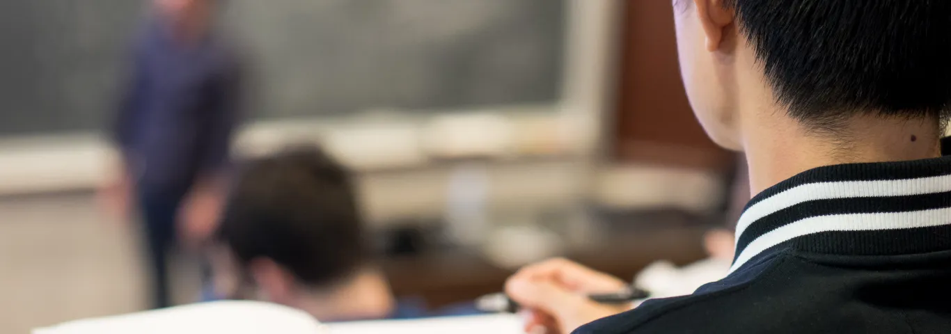 closeup of a student's shoulder as he watches a lecture